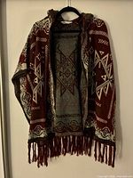 Front view of hooded open-front poncho showing Aztec pattern and fringe hem