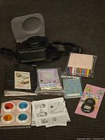 Group shot of camera case, protective shell, photo album, filters, lenses and sticker packs