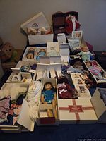 Overview of multiple dolls, trunks, clothing and Pleasant Company boxes laid out