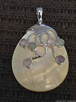Front view of teardrop pendant showing sterling scrollwork and five cabochon stones