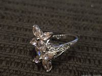 Full view of ring showing floral marquise stone cluster and pavé shoulder