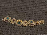 Full view of gold-tone bracelet on fabric background
