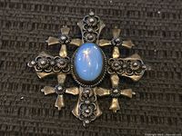 Front view showing cross motif and blue cabochon