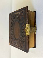 Front and spine view showing embossed leather cover, gilt edges, and clasp