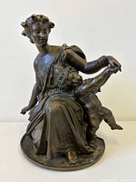 Front view of bronze sculpture showing Diana seated with Cupid