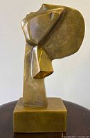 Left profile view of bronze head sculpture showing stylized form and base