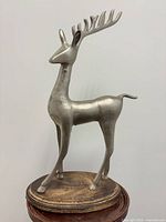Front view of silver-tone metal reindeer on wood base