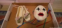 Ballet shoes and clown mask in box