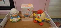 All three Humpty Dumpty items displayed: unboxed bank, boxed bank, wind-up toy
