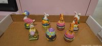 Seven Easter-themed hinged trinket boxes in open cardboard tray