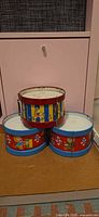 All three Ohio Art tin drums stacked showing overall condition