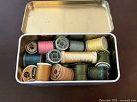 Open tin showing multiple coloured thread spools