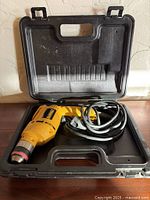 DeWalt yellow corded drill with power cord in open black plastic case