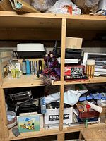 Overall view of shelf showing appliances, flashlights, figurine, tool set and other items