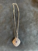 Full view of sterling silver chain with square amethyst and marcasite pendant on dark background