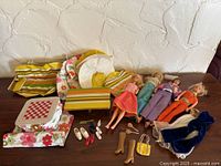 Overview of four dolls with cases and accessories displayed