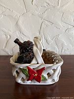 Front view of ceramic basket showing poinsettia decoration and grape bottles inside