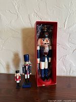 Front view of three nutcracker soldiers with boxed 13" Bloom-Rite figure