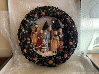 Front view of Brinn's resin Christmas wreath showing full caroling family scene and decorative border