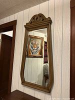 Front view of ornate wood framed wall mirror hung on paneled wall