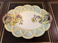 Full view of oval ceramic tray showing grapevine handles and basket-weave rim