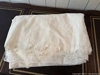 Folded stack of off-white lace fabric showing thickness of yardage