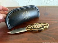 Knife partially open with blade visible beside black zippered case