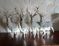 Front angled view of four white flocked reindeer figures