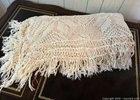 Folded crocheted tablecloth showing fringe detail