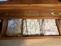 Drawer open showing three stacks of vintage floral bed linens
