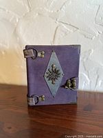 Front cover showing purple leather, metal sunburst accent, latch and corner protectors