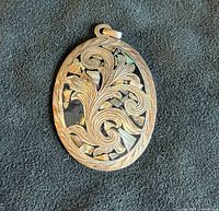 Front view of oval sterling silver overlay pendant with floral design and abalone inlay