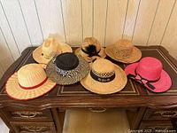 Seven straw hats displayed on desk showing overall variety