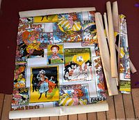 Group of wallpaper rolls with one unrolled showing Toulouse-Lautrec poster graphics