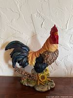 Full view of rooster statue on base with welcome sign