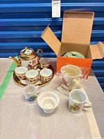 Full lot showing porcelain tea set, cast iron teapot in box, Trappist teapot packaging, mug and infuser