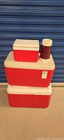 Three stacked Coleman coolers with Thermos jar