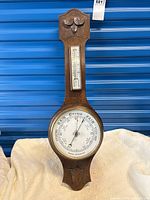 Full view of wood wall barometer/thermometer on backdrop
