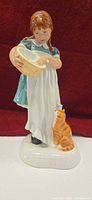 Front view of figurine showing girl, bowl, cat
