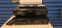 Stacked view of Samsung DVD player on two Sony VCRs with remote