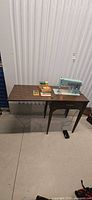 Full view of cabinet with sewing machine, accessories on top, foot pedal on floor
