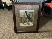 Full view of framed giraffe print on carpeted floor