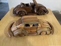 Both carved wooden Volkswagen-style cars on table