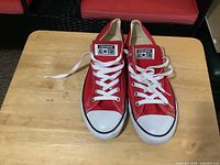 Front view of both sneakers showing red canvas, white laces, toe caps