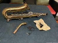 Full view of brass trumpet body, curved bell, separate leadpipe, mouthpiece, brush, cloth