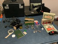 Overview of sewing machine, case, foot pedal, accessories, zigzagger boxes, attachments spread on table
