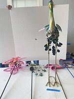 Group view of peacock figure and several stakes on table