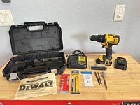 Lot overview showing drill with battery, charger, case, manual, packaged bits, loose bits, belt clip
