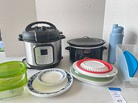 Overview of entire lot including Instant Pot, Crock-Pot, plates, containers, collapsible steamers, bottle, organizer