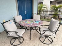 Full patio set showing round table, four swivel chairs, strawberry table cover